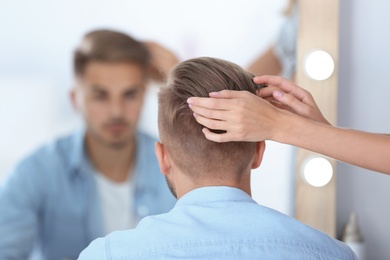 Photo of Professional hairdresser working with young man in barbershop. Trendy hair color