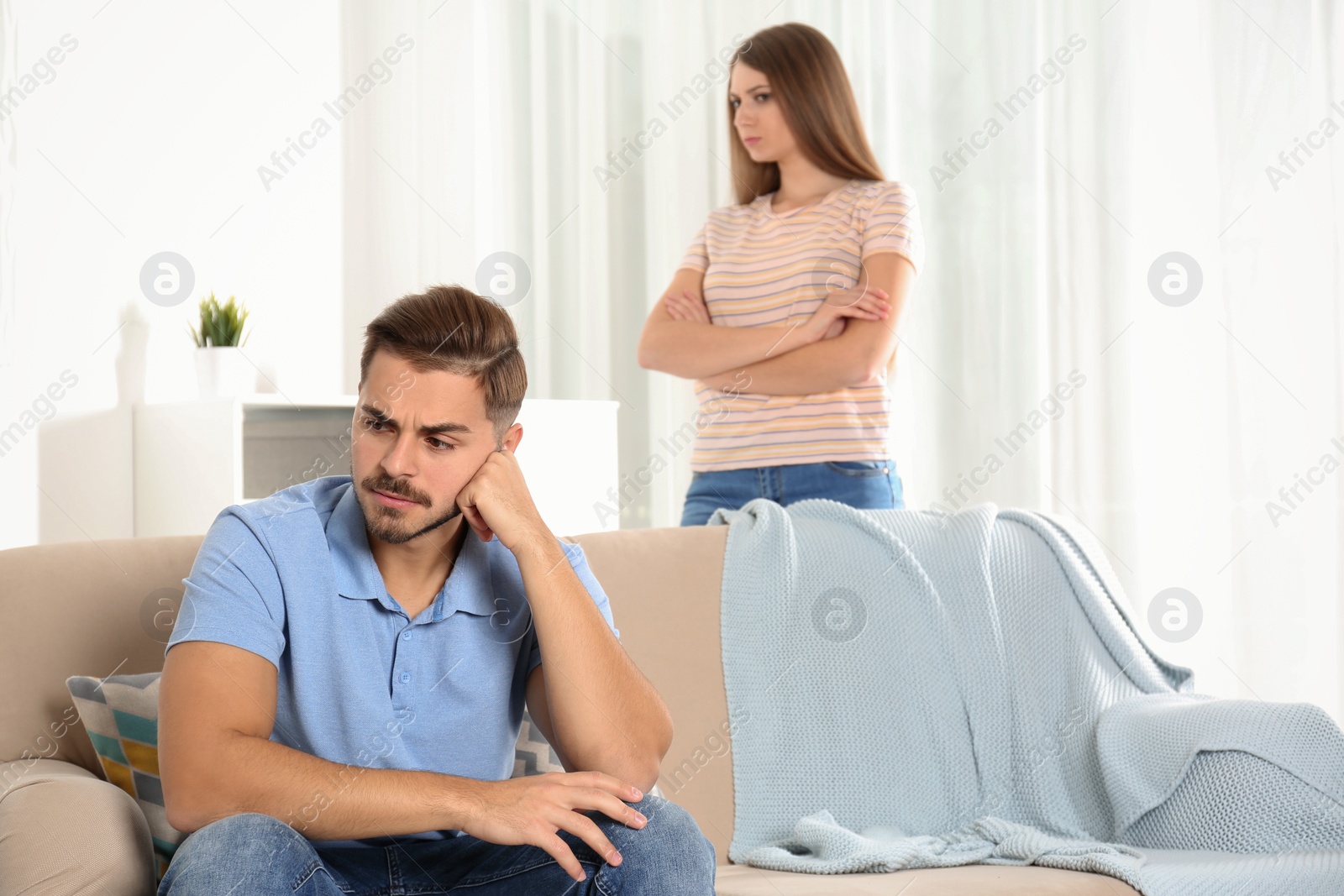 Photo of Young couple arguing in living room. Relationship problems