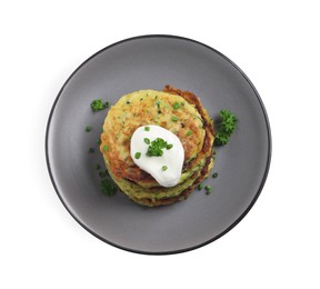 Photo of Delicious zucchini fritters with sour cream isolated on white, top view