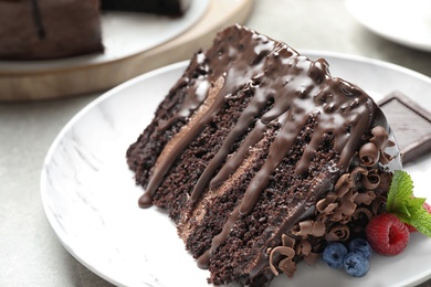 Photo of Piece of delicious chocolate cake decorated with fresh berries on white table, closeup