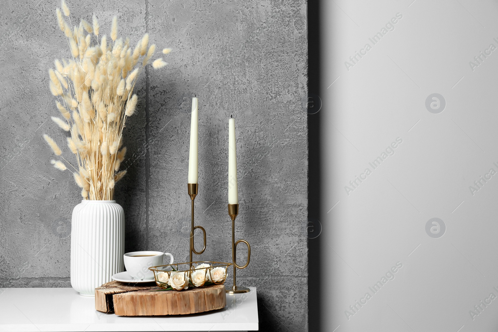 Photo of Cup of coffee, vase and other decor on white table near grey wall indoors, space for text. Interior design