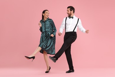 Happy couple dancing together on pink background