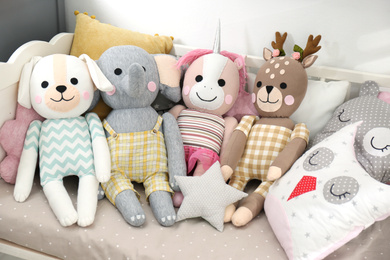 Photo of Cute toys and pillows on bed in baby room. Interior elements