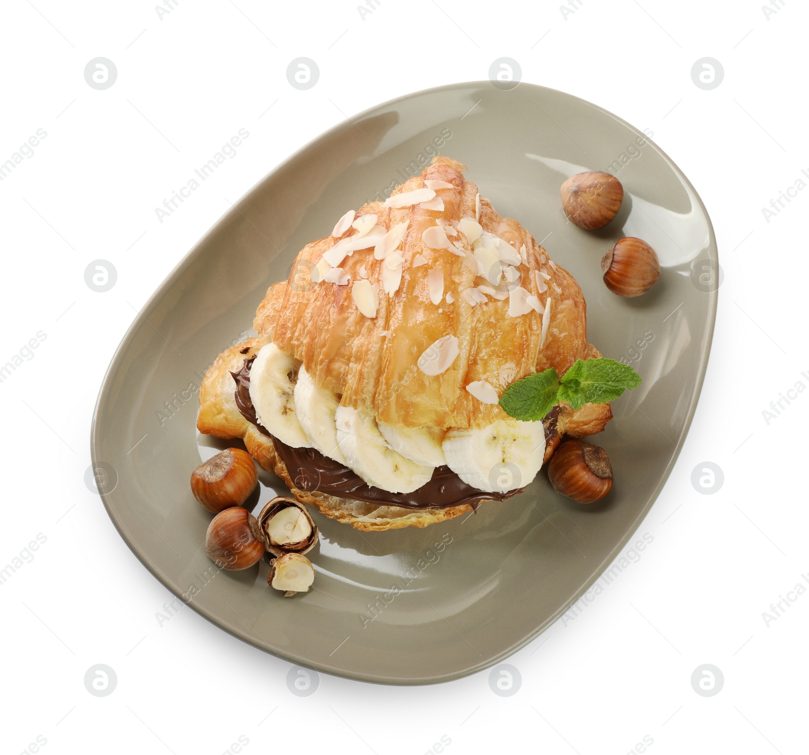 Photo of Delicious croissant with banana, chocolate and hazelnuts isolated on white, top view