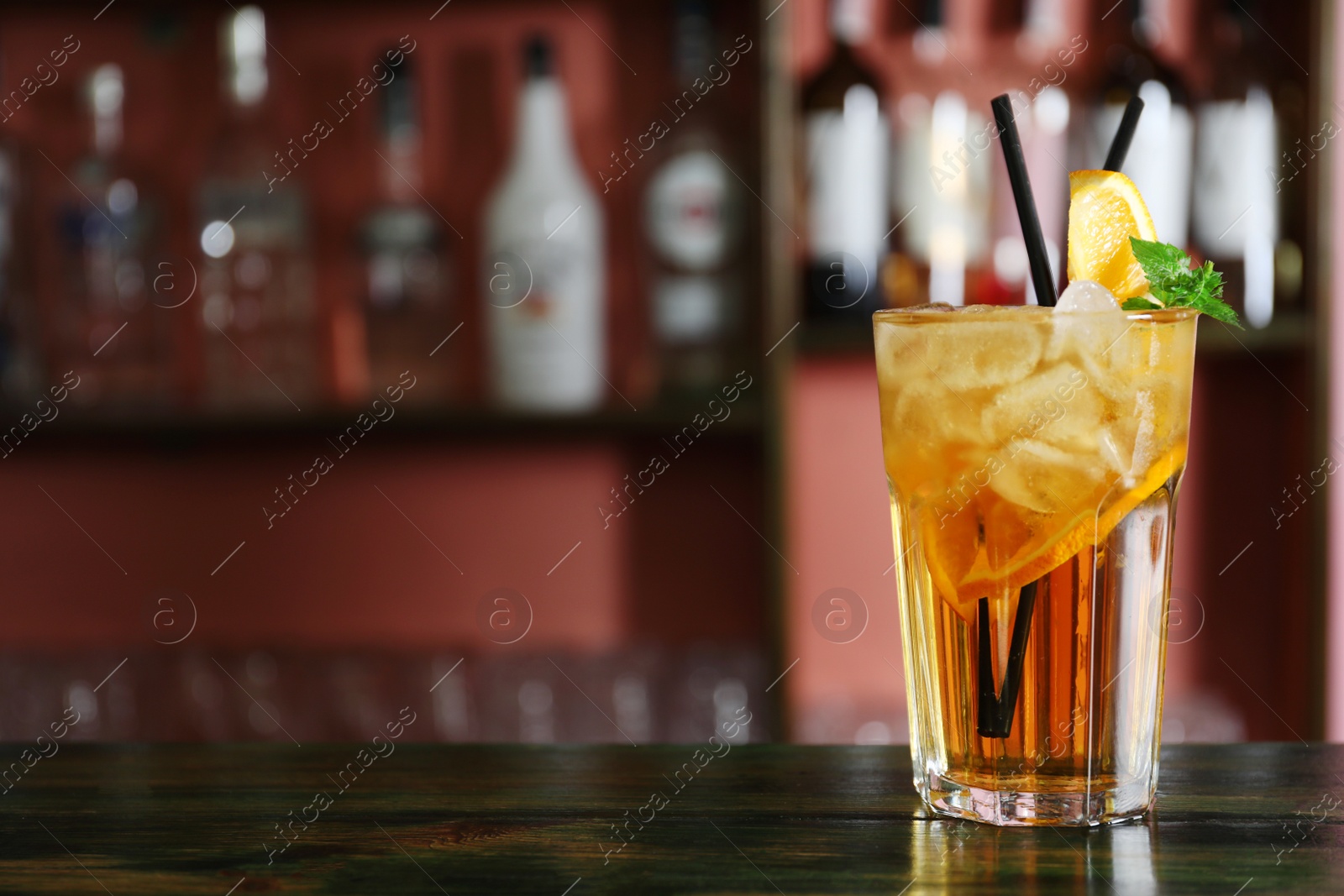 Photo of Glass of delicious cocktail with ice on table in bar