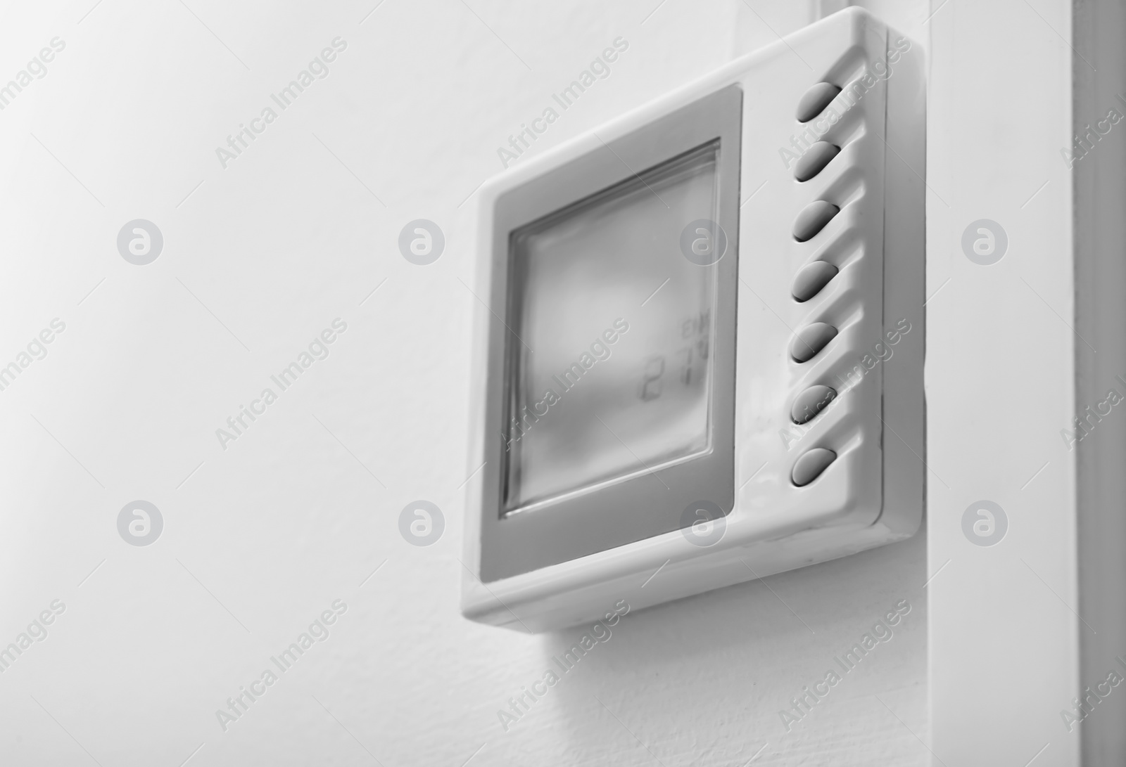 Photo of Modern thermostat on white wall. Heating system