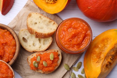 Delicious pumpkin jam and fresh pumpkin on white wooden table, flat lay