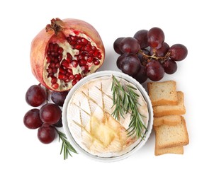 Photo of Tasty baked camembert, croutons, grapes and pomegranate isolated on white, top view
