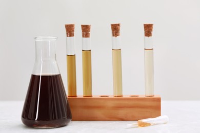 Photo of Laboratory glassware with brown liquids on table against light background