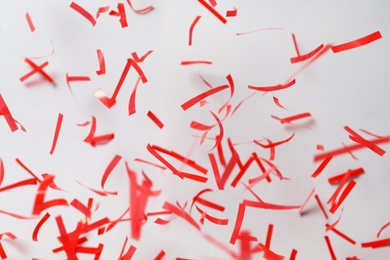 Photo of Shiny red confetti falling down on light grey background