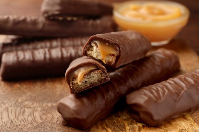Photo of Sweet tasty chocolate bars with caramel on wooden table, closeup