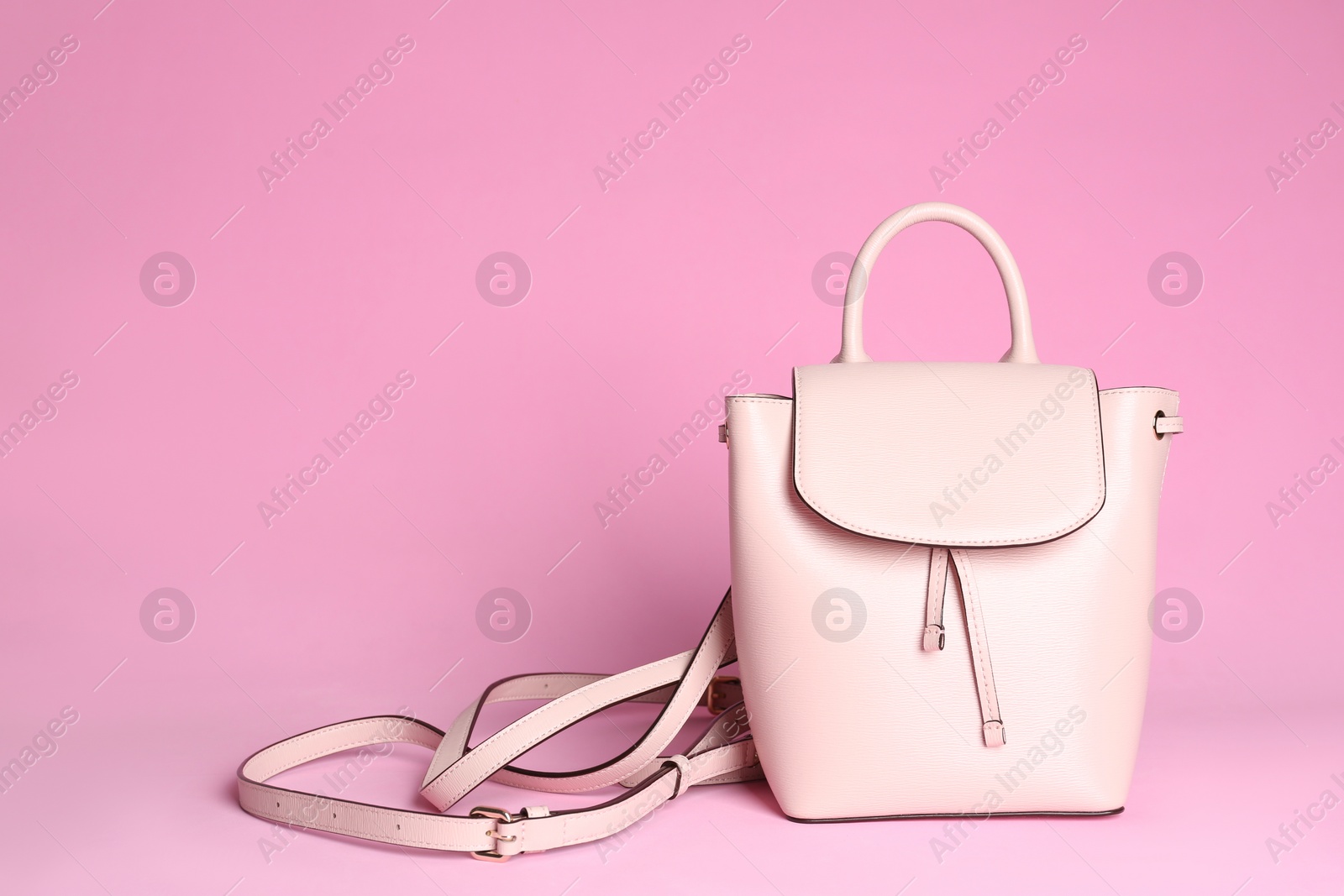 Photo of Stylish woman's backpack on light pink background. Space for text
