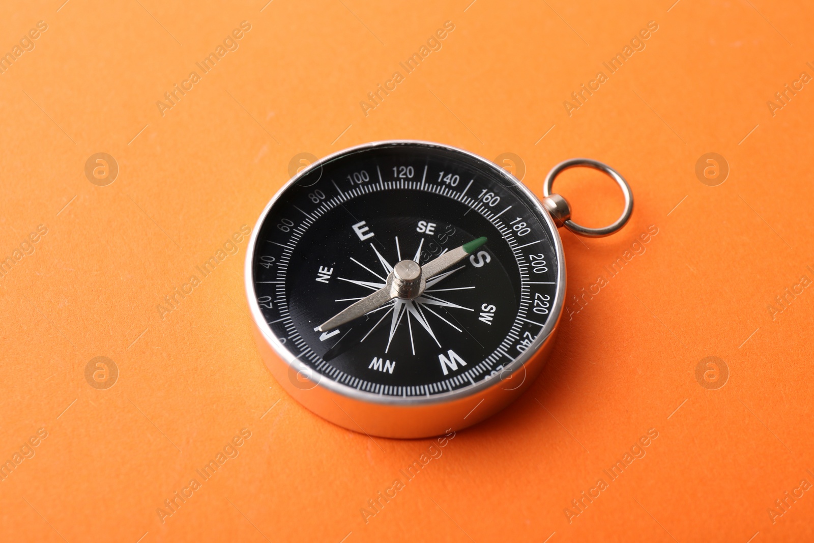 Photo of One compass on orange background. Tourist equipment