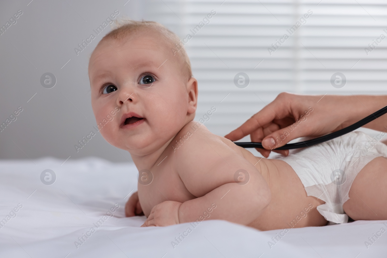 Photo of Pediatrician examining cute little baby with stethoscope in clinic, closeup