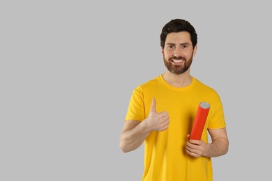 Photo of Happy man with party popper showing thumb up on light grey background. Space for text