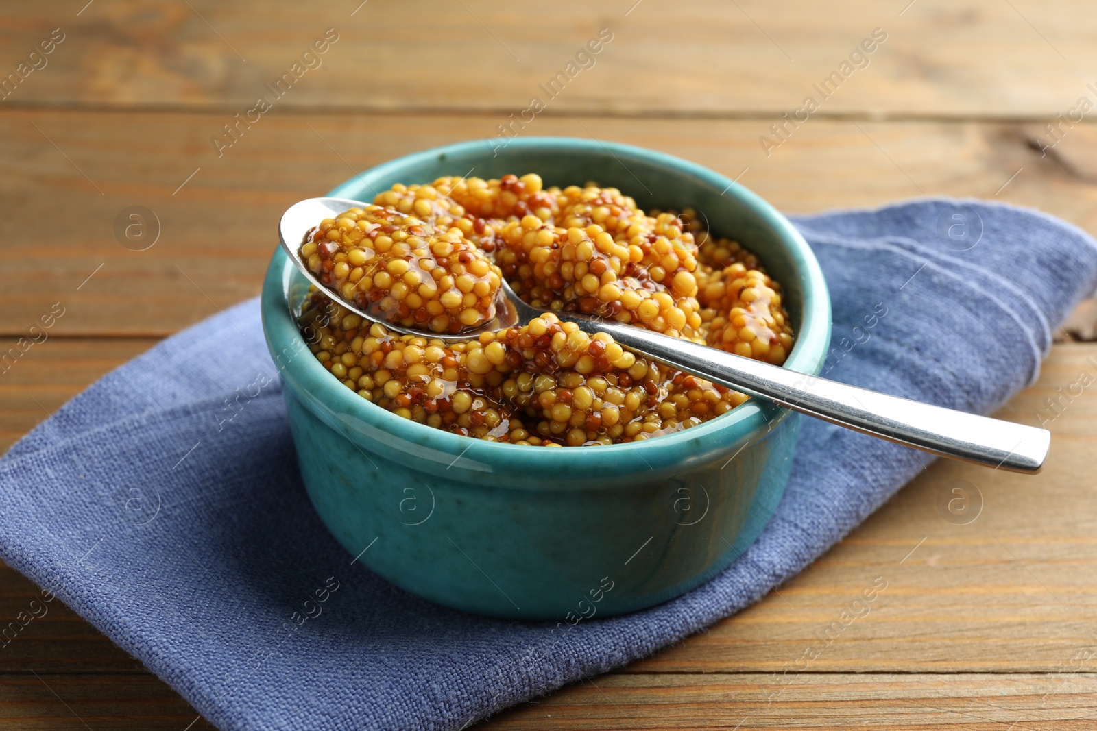 Photo of Whole grain mustard in bowl and spoon on wooden table