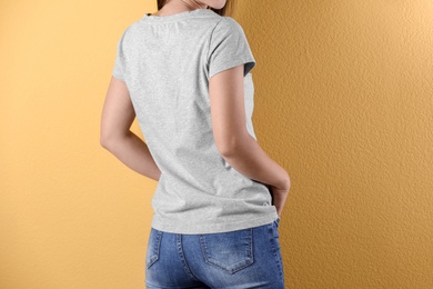 Photo of Young woman in grey t-shirt on color background. Mockup for design