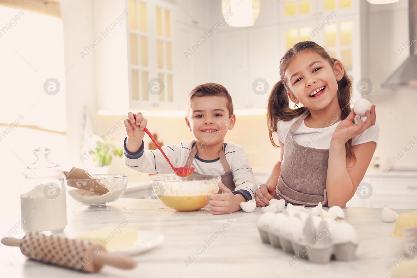 Photo of Cute little children cooking dough together in kitchen