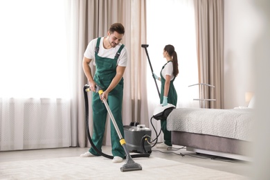 Photo of Team of janitors cleaning bedroom with professional equipment