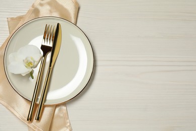 Photo of Stylish setting with elegant cutlery on white wooden table, top view. Space for text