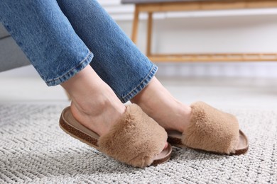 Photo of Woman in brown soft slippers at home, closeup