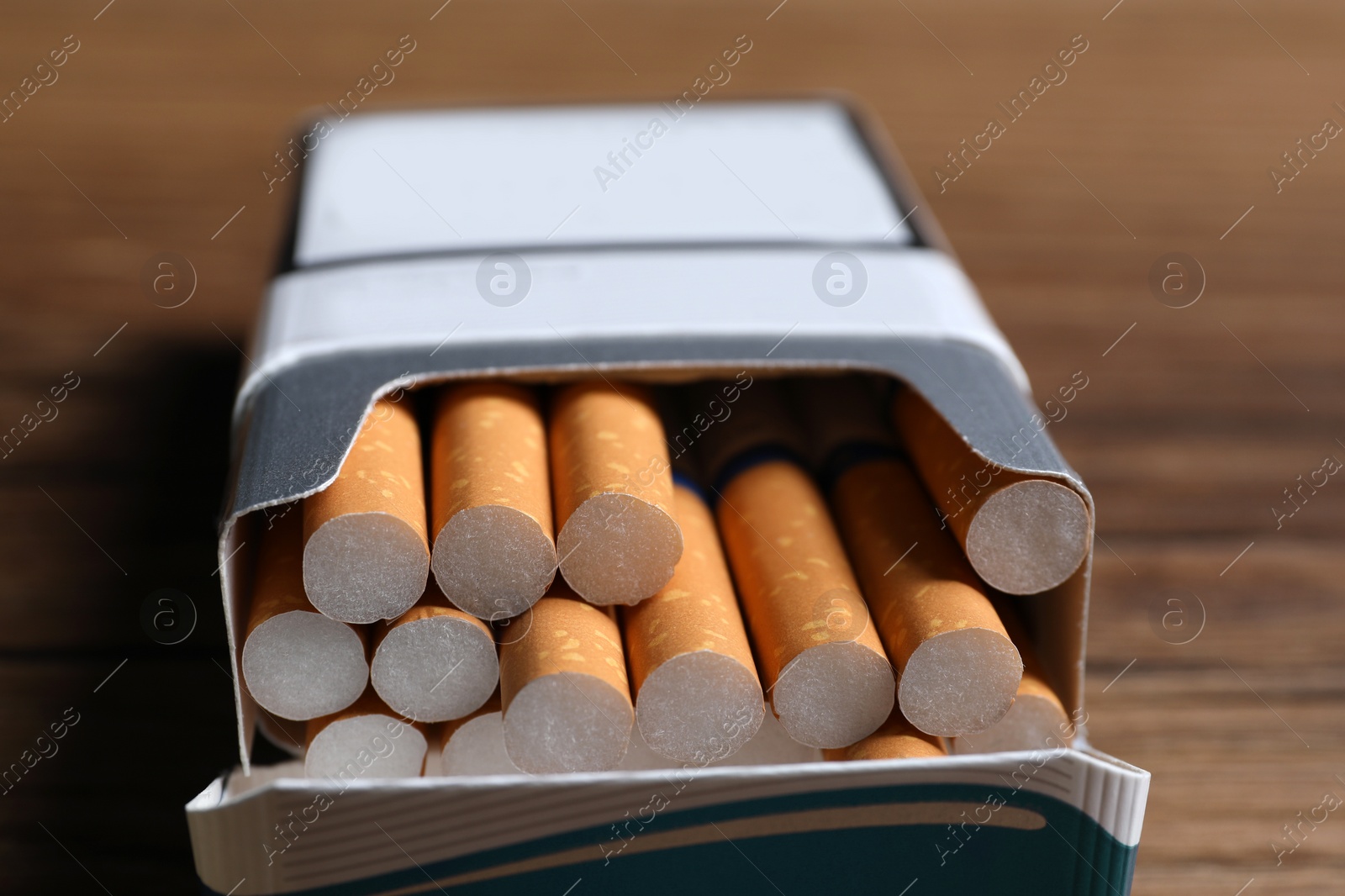 Photo of Cigarettes with orange filters in pack on table, closeup