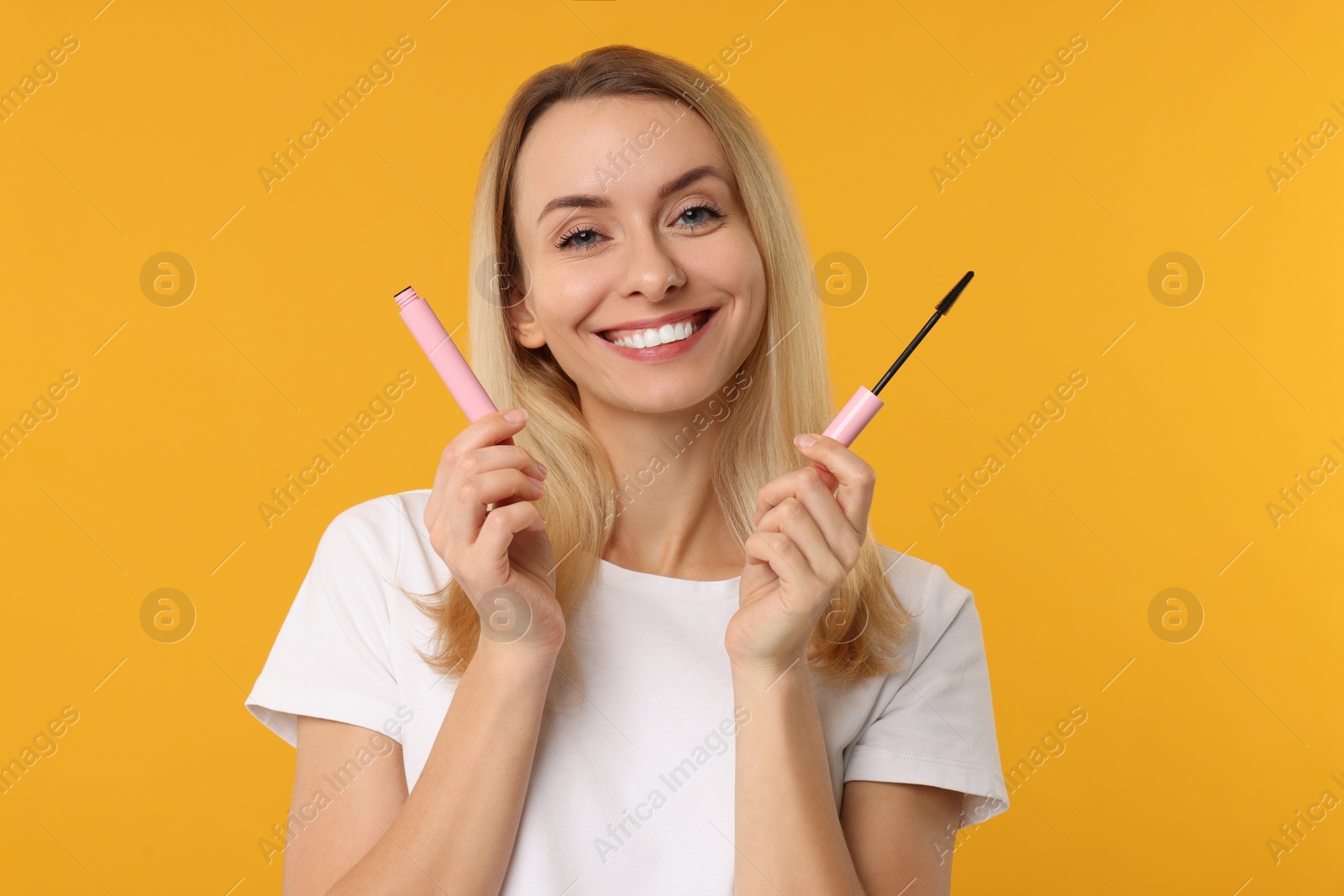 Photo of Beautiful woman with mascara on orange background