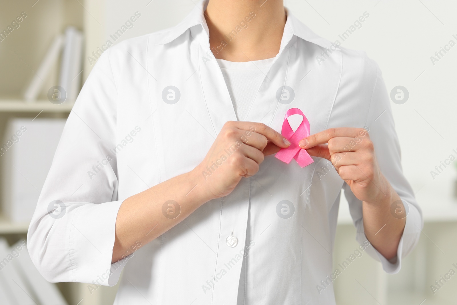 Photo of Mammologist with pink ribbon in hospital, closeup. Breast cancer awareness