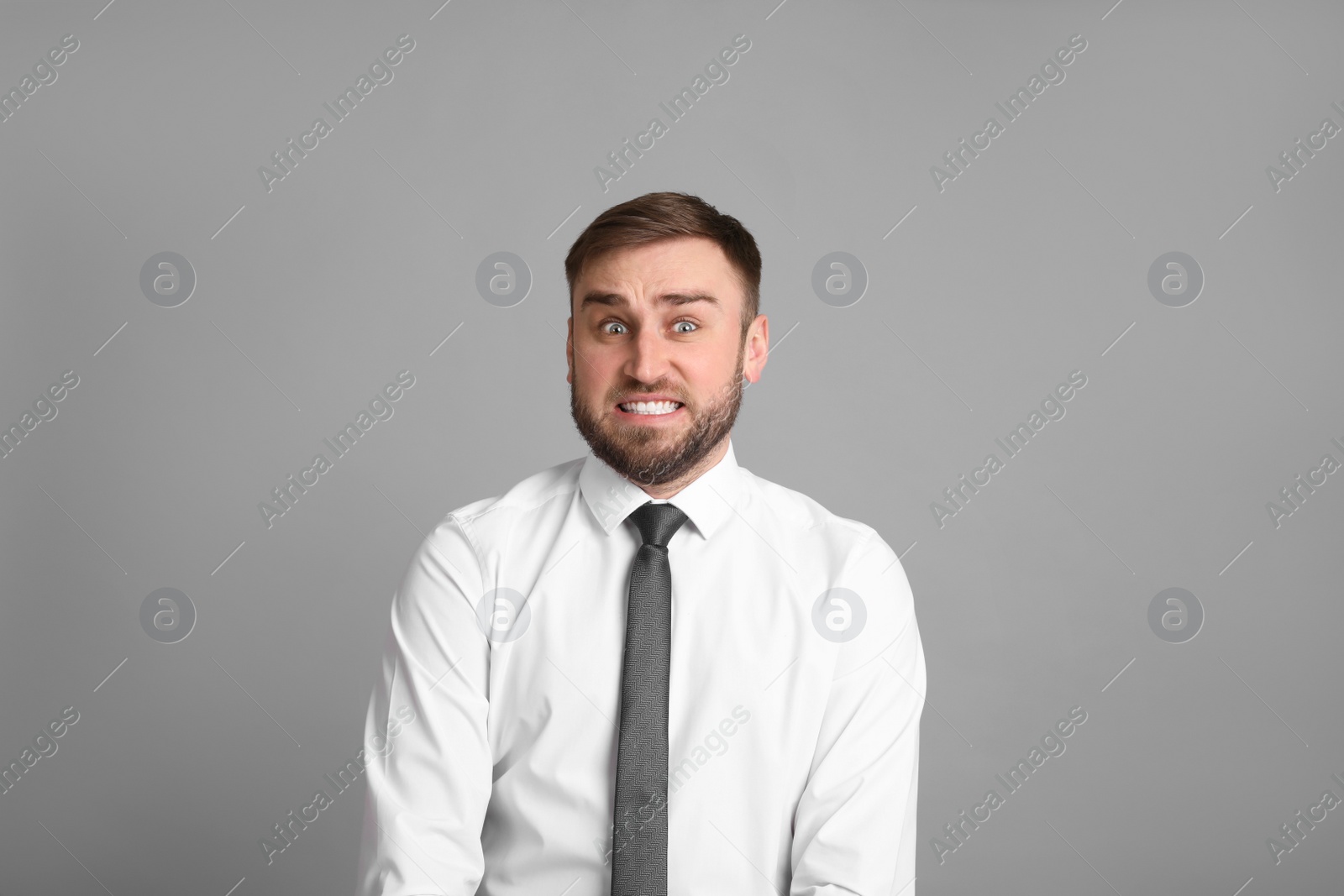 Photo of Portrait of emotional businessman on light grey background. Personality concept