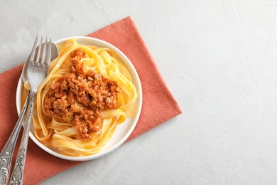 Plate with delicious pasta bolognese on grey background, top view