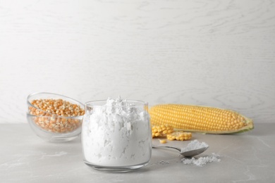 Photo of Jar and spoon with corn starch on table. Space for text