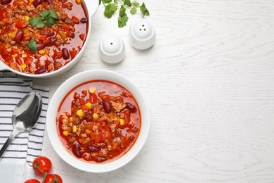 Photo of Tasty chili con carne served on white wooden table, flat lay. Space for text