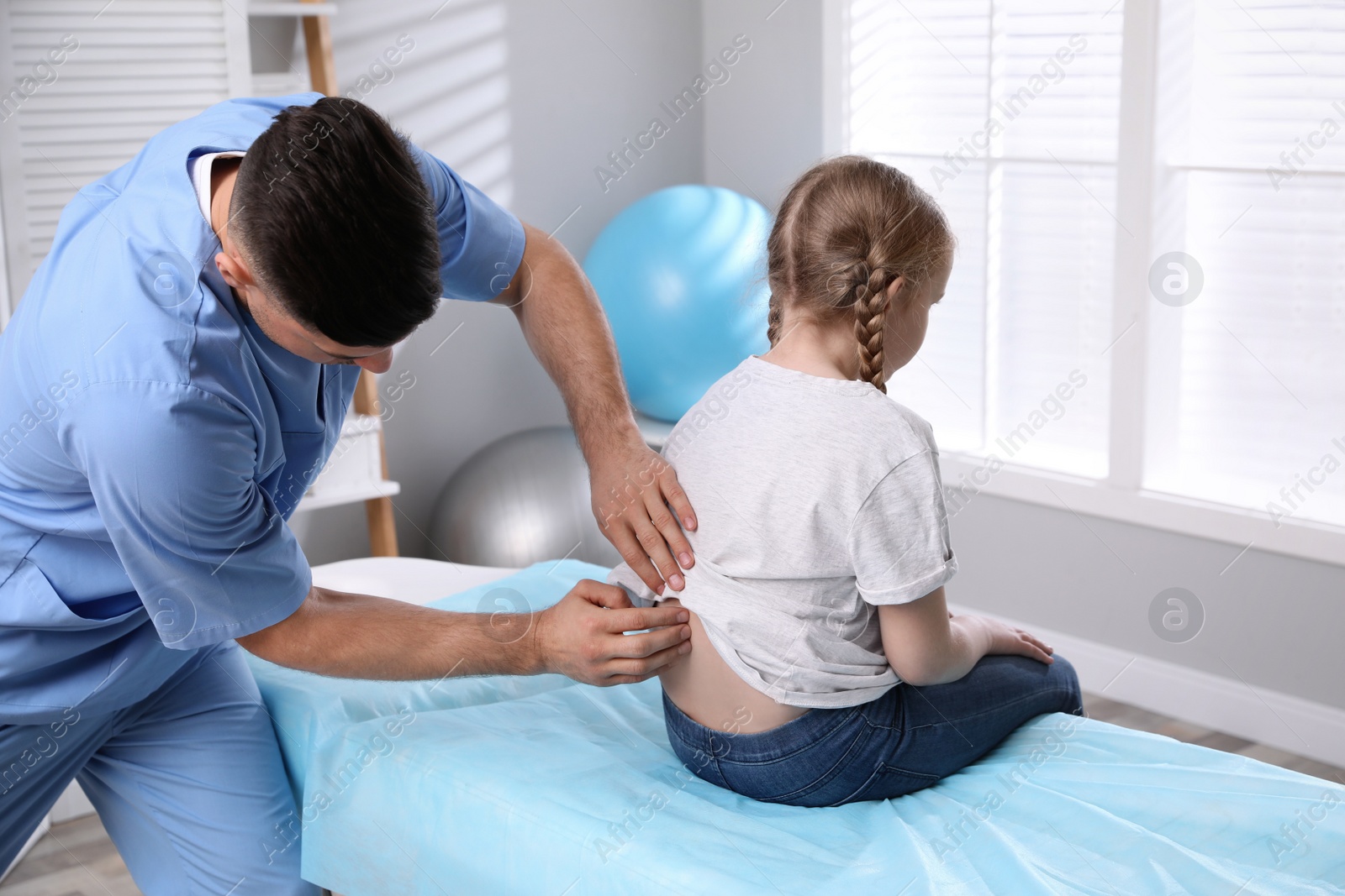 Photo of Orthopedist examining child's back in clinic. Scoliosis treatment