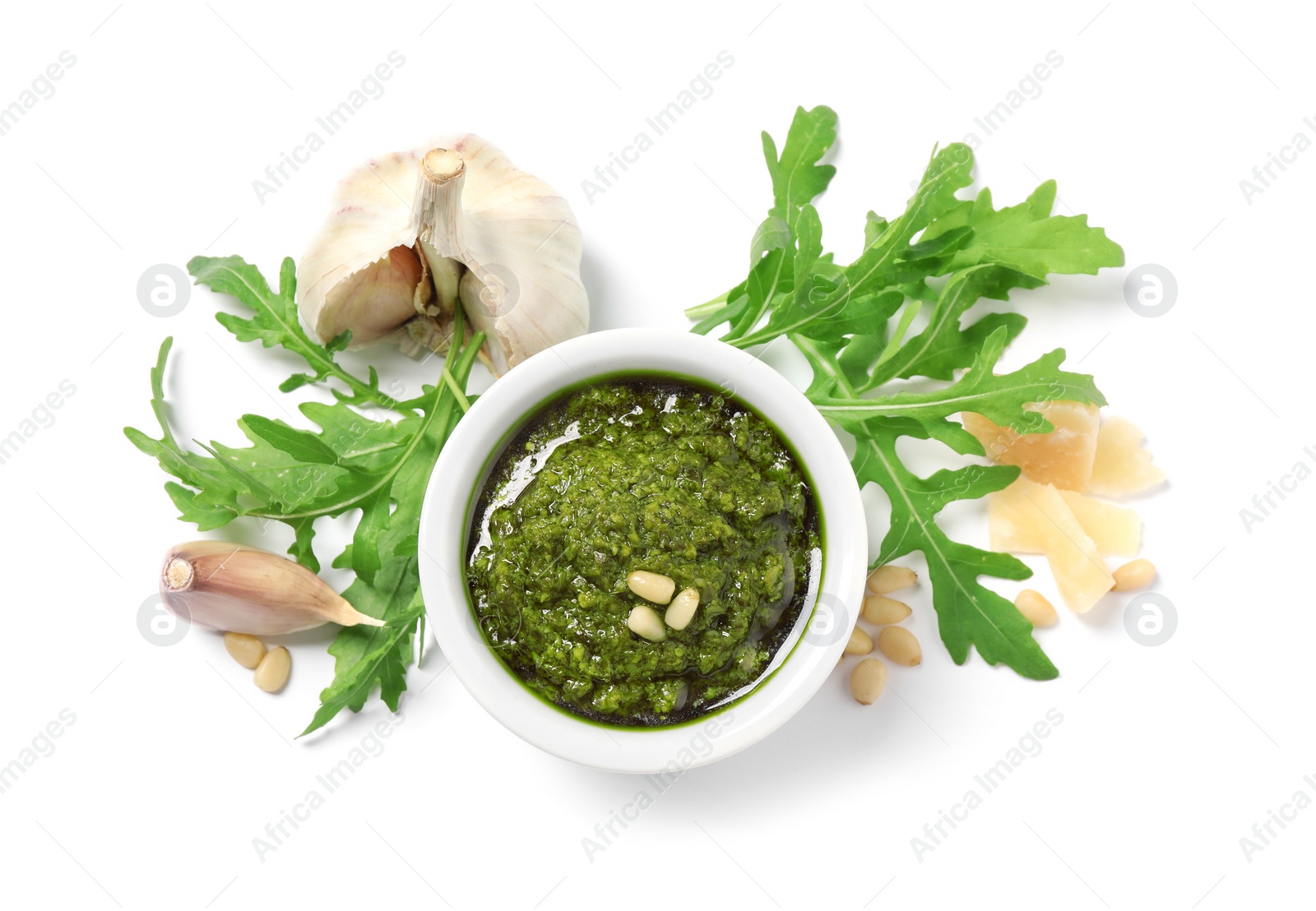 Photo of Bowl of tasty arugula pesto and ingredients on white background, top view