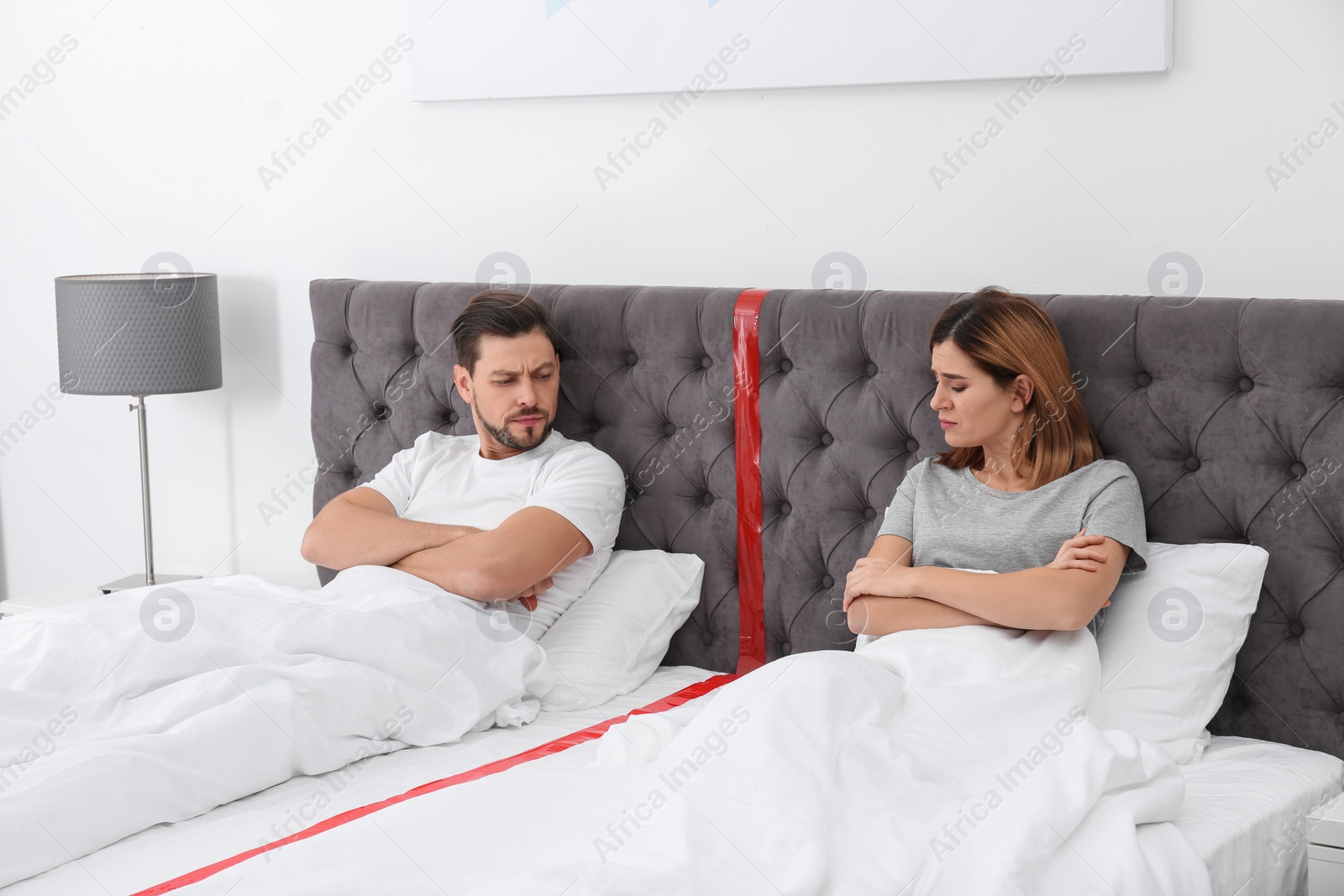 Photo of Upset couple with relationship problems lying separately in bed at home