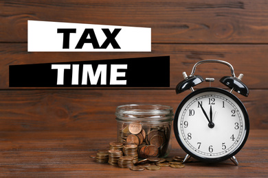 Time to pay taxes. Alarm clock, glass jar and coins on wooden table