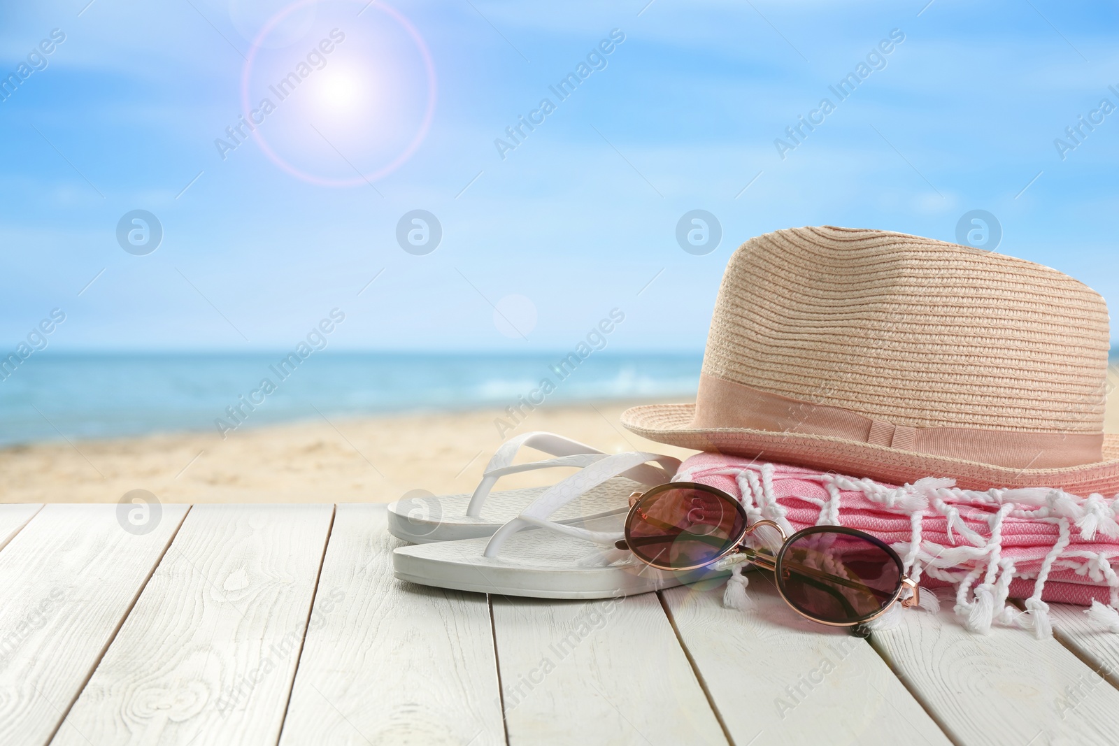 Image of Beach accessories on white wooden surface near ocean, space for text