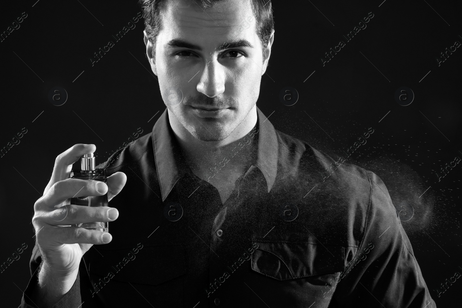 Photo of Handsome young man spraying perfume, black and white effect