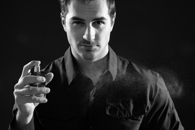 Photo of Handsome young man spraying perfume, black and white effect