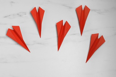 Many handmade paper planes on white marble table, flat lay