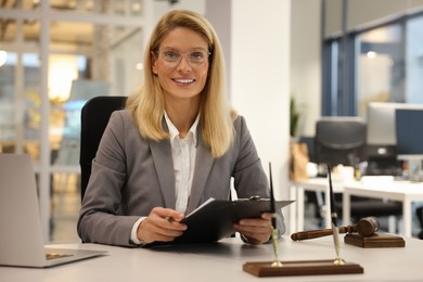 Photo of Portrait of smiling lawyer with clipboard working at table in office