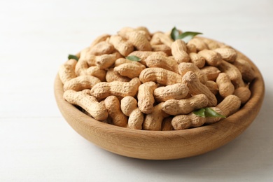 Photo of Bowl with peanuts in shell on table