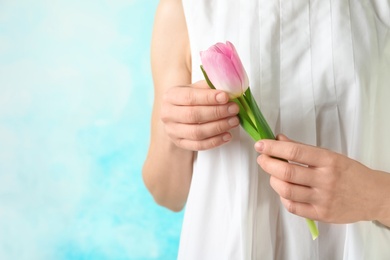 Photo of Girl holding beautiful spring tulip on color background, closeup with space for text. International Women's Day