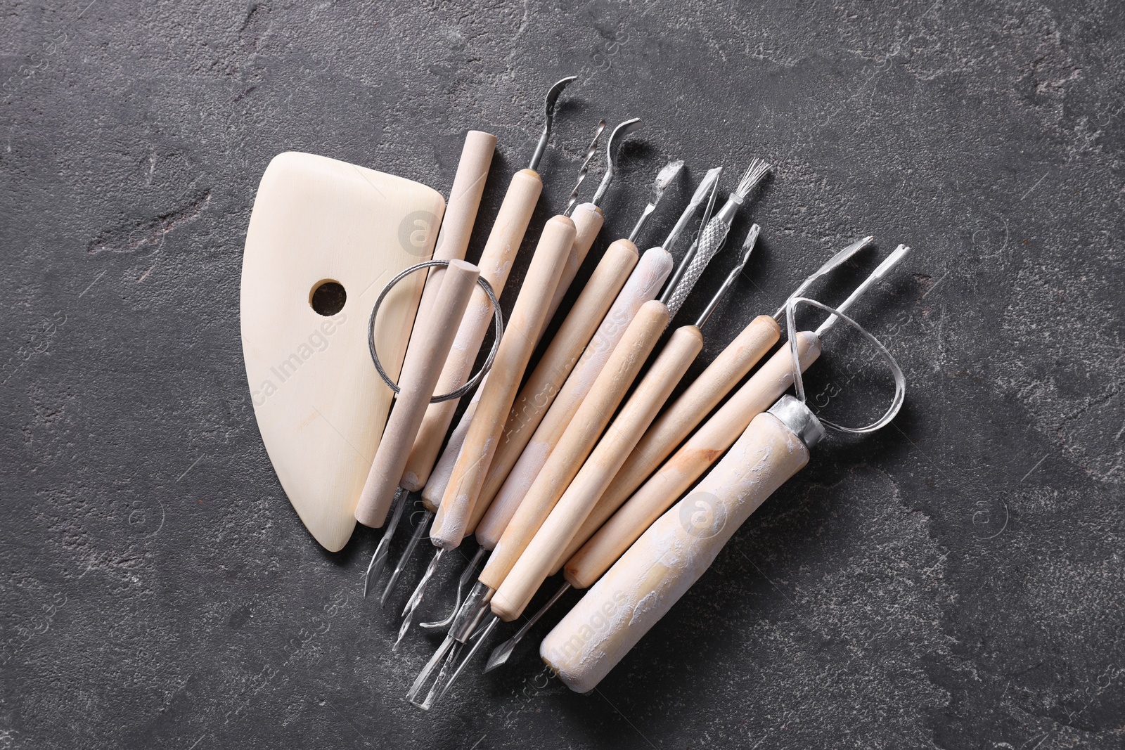 Photo of Set of different clay crafting tools on grey table, top view