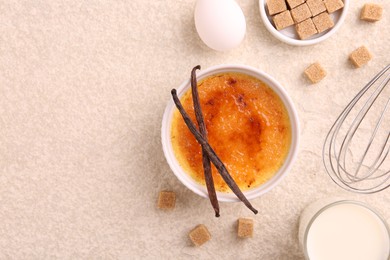 Photo of Delicious creme brulee in bowl and ingredients on light textured table, flat lay. Space for text