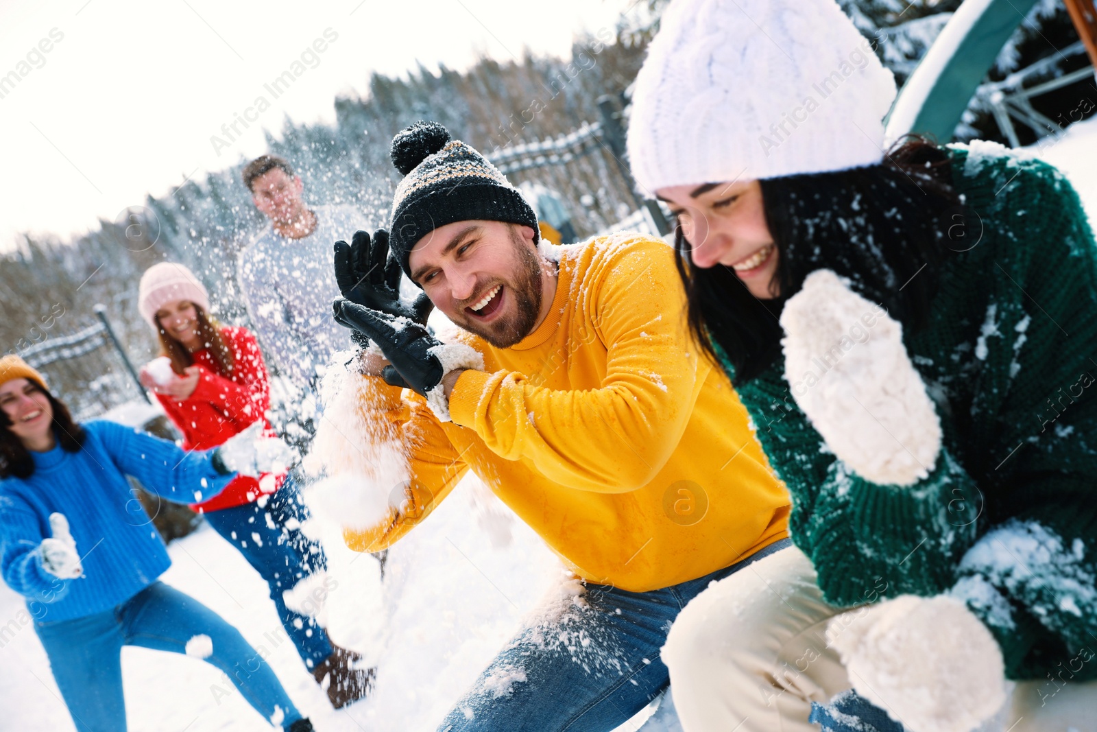 Photo of Group of friends playing snowballs outdoors. Winter vacation