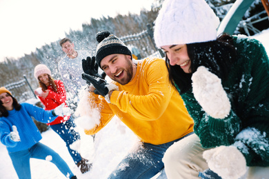 Group of friends playing snowballs outdoors. Winter vacation