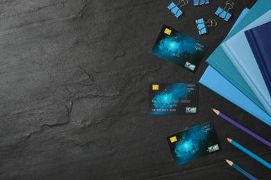 Credit cards and stationery on black background, flat lay. Space for text
