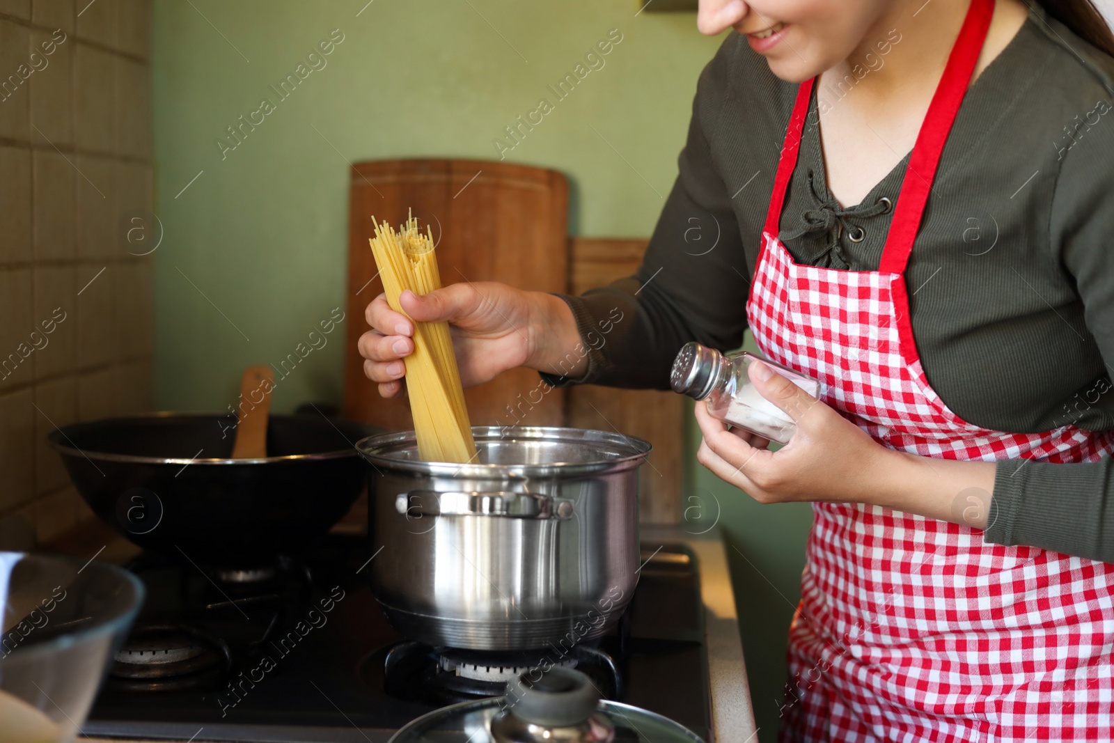 Photo of Woman cooking spaghetti on stove in kitchen, closeup