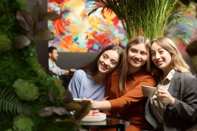 Photo of Young women flirting with guys at next table in cafe